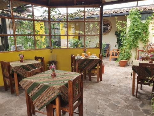 un restaurante con mesas, sillas y ventanas en Hospedaje Familiar Kitamayu Pisac en Pisac