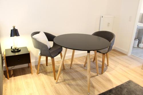 uma mesa e duas cadeiras e um candeeiro num quarto em Moderne 1-Zimmer Wohnung mit Terasse, Küche, Bad mit Dusche, TV & WIFI em Burgwedel