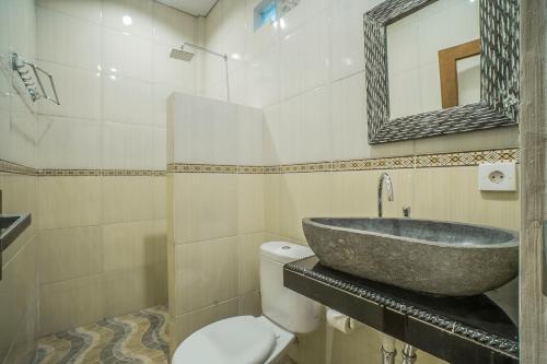 een badkamer met een wastafel, een toilet en een spiegel bij Adenia House Ubud in Ubud