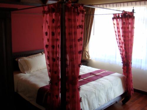 a bedroom with a canopy bed with red curtains at Sunset Apartment Phuket in Patong Beach