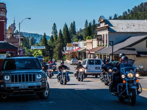 a group of people riding motorcycles down a street at Mariposa Lodge in Mariposa