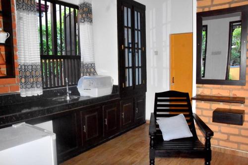 a kitchen with a chair and a sink and windows at Rovenluck Eco Cabana in Weligama