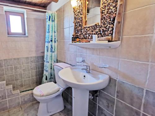a bathroom with a sink and a toilet and a mirror at Guesthouse Toxotis in Pirgos Dhirou