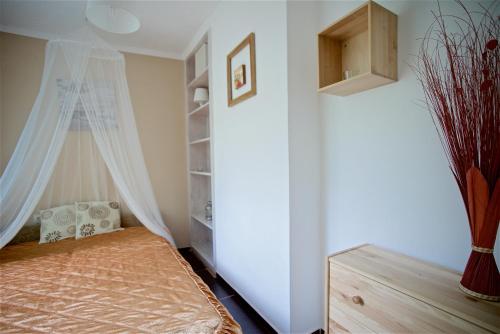 a bedroom with a bed with a curtain and a window at Aranypart Vendégház - Tiszakécske in Tiszakécske