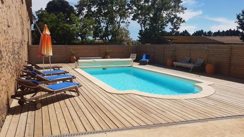 - une piscine sur une terrasse avec des chaises et un parasol dans l'établissement Le Gite de la Prunette, au Grau-dʼAgde