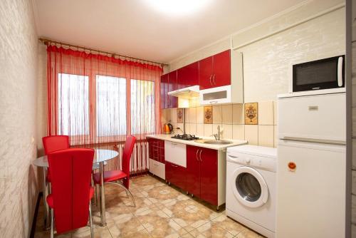 a kitchen with red cabinets and a table and a washing machine at Apartment on Staroobriadnytska 3 in Kherson