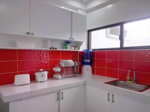a kitchen with white cabinets and red tiles at Diodeth's Apartments in Butuan
