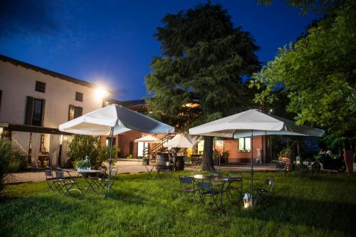 due tavoli e sedie con ombrelloni in un cortile di notte di Agriturismo Le oche selvatiche a Lauzacco