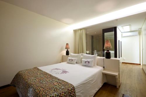 a bedroom with a large white bed with two lamps at Quinta Rainha Santa Mafalda in Pinhão