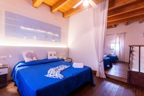 a bedroom with a blue bed with blue sheets and wooden ceilings at Residence Duna Rossa in Duna Verde