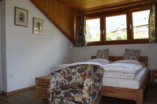 a bedroom with a bed with a chair and a window at Residence La Terrazza in Caldaro