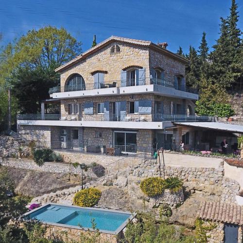 une grande maison en pierre avec une piscine en face de celle-ci dans l'établissement Au Pied des Baous, à Vence