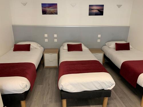 a room with three beds with red and white sheets at La Ferme Des Barmonts in Villejuif