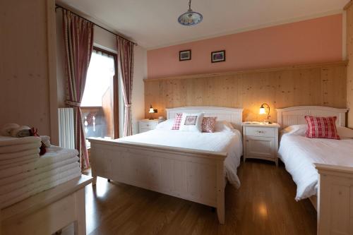 a bedroom with two white beds and a window at Casa Sofia in Valdisotto