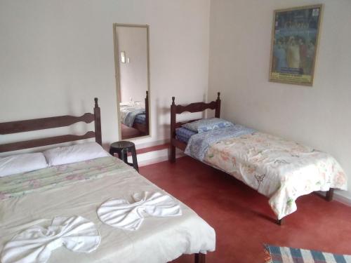 a bedroom with two beds and a mirror at Hospedaria Cosanostra in Itaúnas