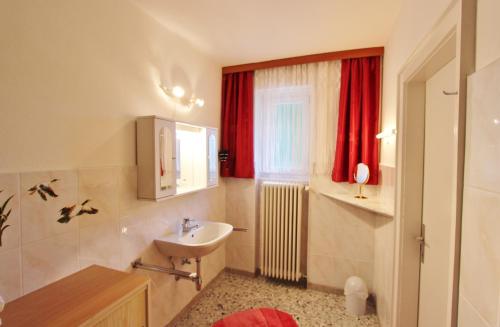 a bathroom with a sink and a toilet and red curtains at Ferienhaus Hollinger in Afritz