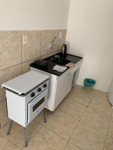 una pequeña cocina con fogones y fregadero en Apartamento beira da Praia das Ondinas en São Lourenço do Sul