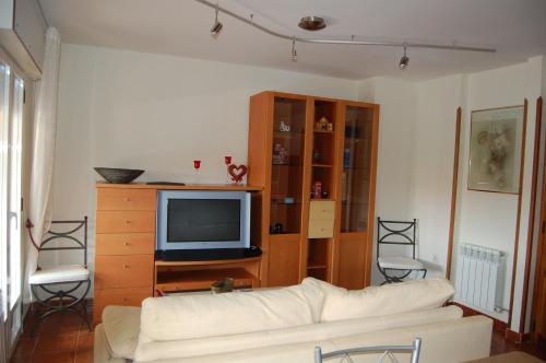 sala de estar con sofá blanco y TV en Casa Cascabelera, en Ayllón