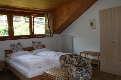 a bedroom with a bed and a chair and windows at Residence La Terrazza in Caldaro