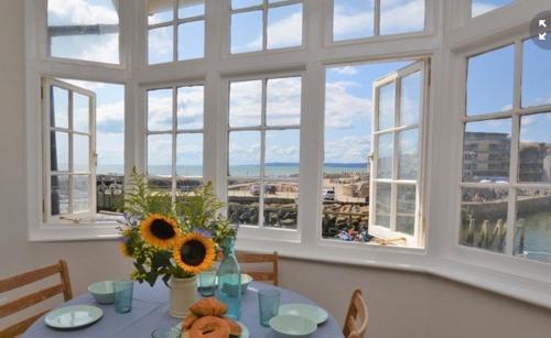 a dining room with a table with a vase of sunflowers at Harbour View, Pier Terrace in West Bay