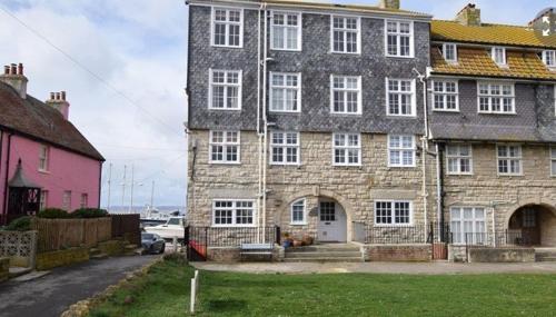 a large brick building with a bench in front of it at Harbour View, Pier Terrace in West Bay