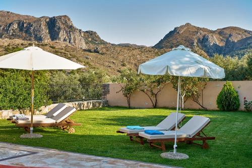 two chairs and umbrellas on a lawn with mountains at Mouri Villa in Mouríon