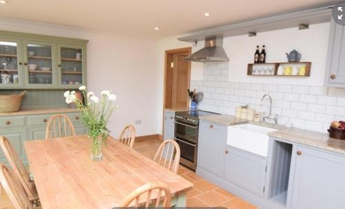 a kitchen with a table with a vase of flowers on it at Little Wandas in Uplyme