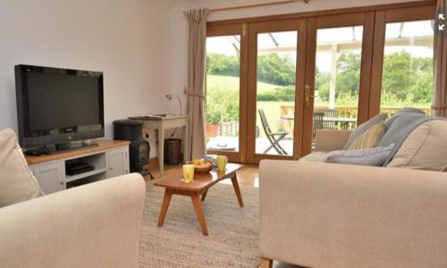 a living room with a couch and a tv and a table at Little Wandas in Uplyme