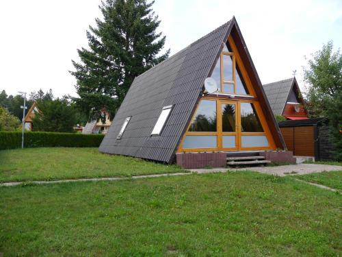 una pequeña casa con techo de gambrel y una gran ventana en Ferienhaus im Nordschwarzwald - Nurdachhaus in Waldrandlage Haus Florine, en Schellbronn