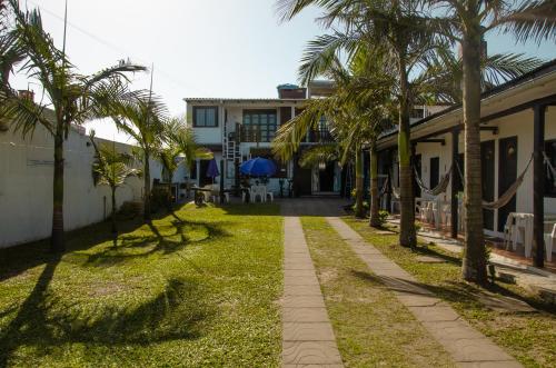 a walkway with palm trees next to a building at Pousada Aventura in Passo de Torres