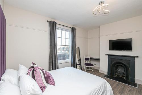 a bedroom with a white bed and a fireplace at Pages Hotel and Guesthouse in Harlow