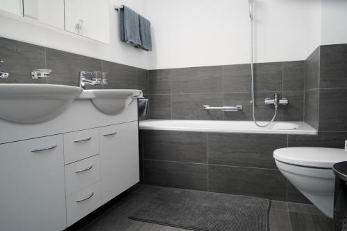 ein Badezimmer mit einem Waschbecken, einer Badewanne und einem WC in der Unterkunft Wohnen wie Zuhause in Sagogn