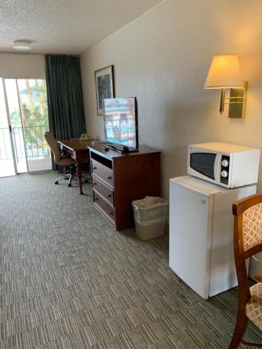 a hotel room with a microwave and a desk with a computer at Desert Hot Springs Spa Hotel in Desert Hot Springs