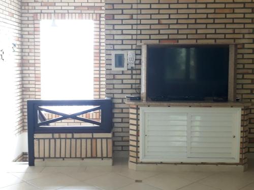 un televisor sentado en un stand junto a una pared de ladrillo en Casa de Pedra - 14 pessoas - Bombinhas IMB2, en Bombinhas
