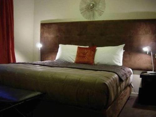 a bedroom with a large bed with two pillows at Terra Vive Suites & Apartments in Christchurch