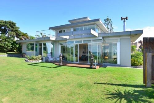 a large house with people standing in a yard at Room with amazing seaview in Whangaparaoa