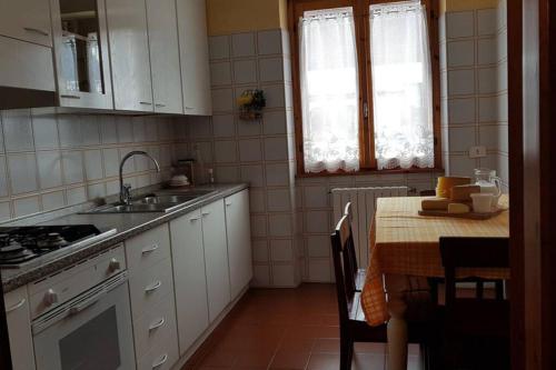 una cucina con mobili bianchi e un tavolo con un lavello di Baita nei pra a Bormio