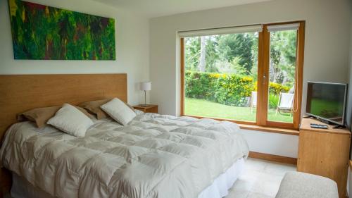 Un dormitorio con una cama grande y una ventana en Quinto Elemento Bariloche en San Carlos de Bariloche