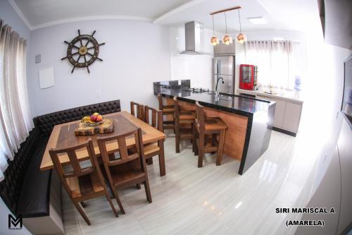 cocina y comedor con mesa y sillas en Siri Mariscal, en Bombinhas
