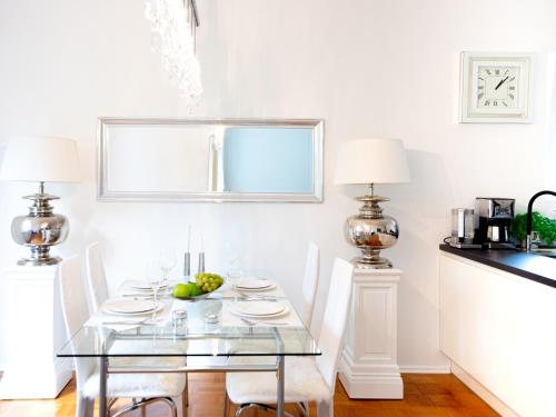 a dining room with a glass table and white chairs at Family Apartment City Center Baden-Baden in Baden-Baden
