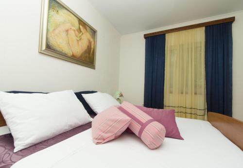 ein weißes Bett mit rosa und weißen Kissen darauf in der Unterkunft Apartments Dijana - 20m from the sea in Prigradica