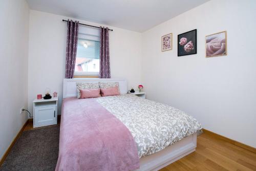 a bedroom with a pink and white bed with a window at Apartman NIVA Daruvar in Daruvar