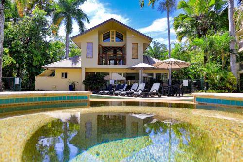 a house with a swimming pool in front of a house at Port Douglas Sands Resort in Port Douglas