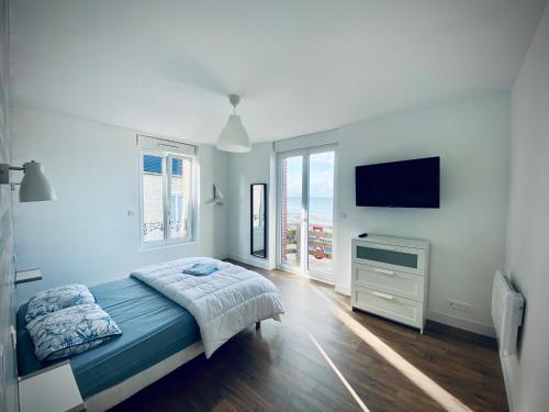 um quarto com uma cama e uma televisão de ecrã plano em Gîte « La Vague » 8-10 pers em Grandcamp-Maisy