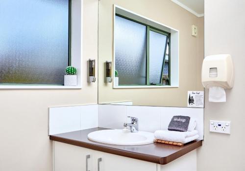 a bathroom with a sink and two windows at Barringtons Motor Lodge in Whakatane