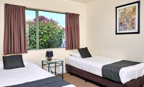 two beds in a room with a window at Barringtons Motor Lodge in Whakatane