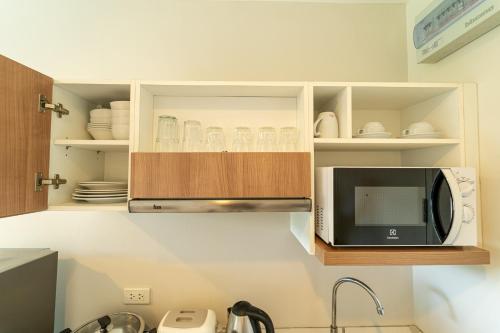 a kitchen with a microwave and some plates and cups at ZcapeX2 in Bang Tao Beach