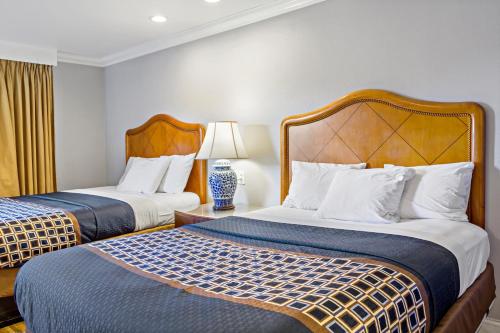 ein Hotelzimmer mit 2 Betten und einer Lampe in der Unterkunft Highlander Motel in Oakland