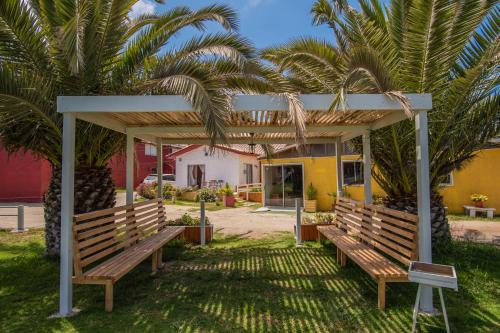 two benches under a pergola in front of a house at Cabañas Maihue in La Serena