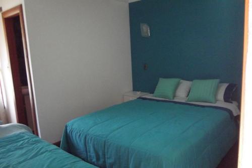 a bedroom with two beds with blue walls at Refugio de Caty in Bahía Mansa